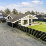 Modern villa with large garden and playground. Black timber structure and glass facade.