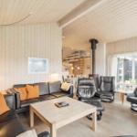Living room with sofa, chairs, and fireplace. Wooden walls and ceiling.