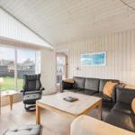 Living room with wooden walls, sofa, TV, and large window.