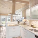 Kitchen with white cabinets, stainless steel sink, and wood paneling.