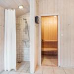 Shower with curtain and sauna in wooden house.