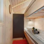 A bedroom with wooden walls, a bed, and a window. Two duck figures sit on the bed.