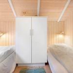 Two beds flank a white wardrobe in a wooden room.