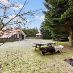 House with garden, picnic table, and trees. Frosted lawn and wooden bench.