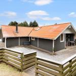 House with orange roof and wooden terrace, surrounded by a wooden fence.