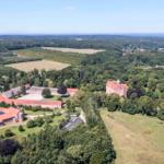 Rural property with multiple buildings and surrounding forests and fields.