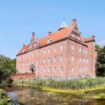 Red brick building with red roof and white windows by the water.