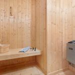 Sauna with wooden walls, bench, bucket, towel, and stones.