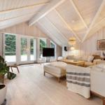 Living room with wooden walls, sofa, TV, and large windows.