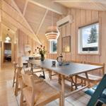 Dining room with wooden walls, table, chairs, window, and ceiling light.