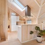Kitchen with wooden walls and skylight. White built-in appliances and wooden chairs.