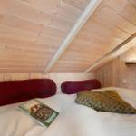 Bedroom with wooden walls and bed with pillows and book.