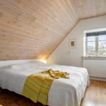 Schlafzimmer mit Holzdach, Bett und Fenster