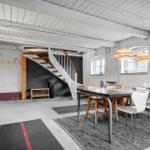Esszimmer mit Tisch, Stühlen und Wendeltreppe. Decke mit Balken und Fenster.