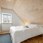 Schlafzimmer mit Holzdecke, weißem Bett und Fenster mit Blick nach draußen.