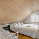 Schlafzimmer mit Holzdecke, Bett und Fenster. Holzfußboden und Nachttisch.
