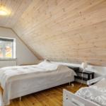Schlafzimmer mit zwei Betten, Holzdecke und Fenster.