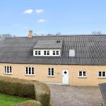 Ein hellgelbes Haus mit grauem Dach und weißer Tür.