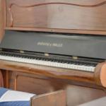 A piano with open lid and sheet music on the stool.