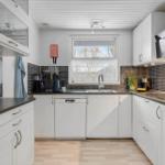 Kitchen with white cabinets, dark countertops, and window with view outside.