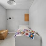 A bedroom with a bed, a basket, and a lamp.