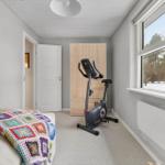 Room with exercise bike, bed, and window view of forest