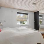 Bedroom with bed, window, and mirrored doors. Wooden ceiling and white walls.