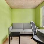 A room with green walls, sofa, desk, and window.