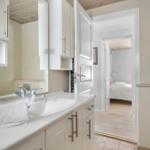 Bathroom with sink, mirror, and toilet. View into bedroom with bed.