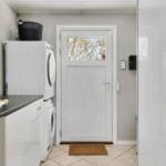 Entrance with washer and dryer, door with glass panel and doormat.
