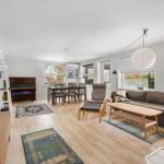Living and dining area with sofa, table, piano, and windows.