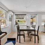 Dining room with table, chairs, and piano. Windows and door to terrace.