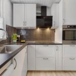 Kitchen with white cabinets, dark countertop, and oven.