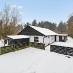 House with snow-covered roof and wooden railing in winter.