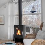 Living area with wood stove, wicker furniture, and view to outside.