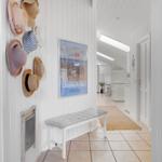 Entryway with bench, wall poster, and dried hats hanging on the wall.