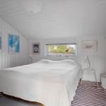 Bedroom with white bed, window, and wall art.