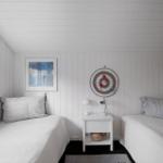 Two beds with striped pillows, nightstand with lamp and target on wall.