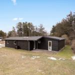 Modern wooden cabin with terrace and garden. Surrounded by forest and grassland.