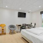 Bedroom with bed, desk, TV, and view of garden.