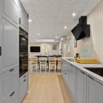 Kitchen with gray cabinets, countertop, and window. Dining area with table and chairs in the background.