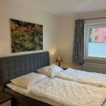 Schlafzimmer mit Doppelbett, Wandbild und Fenster mit Blick.