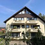 Modernes Mehrfamilienhaus mit Balkonen und grüner Umgebung.