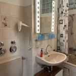 Badezimmer mit Waschbecken, Spiegel, Dusche und Handtuchhalter.