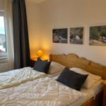 Schlafzimmer mit Bett, Nachttischen und Fensterblick auf Dächer.