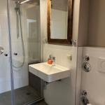 Badezimmer mit Dusche, Waschbecken und Spiegel.