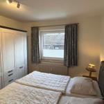 Schlafzimmer mit Doppelbett, Kleiderschrank und Fenster mit Vorhängen.