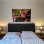 Schlafzimmer mit Bett, Nachttischen und Wandbild mit Pilzen.