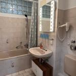 Badezimmer mit Badewanne, Spiegel und Toilette.