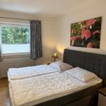 Schlafzimmer mit Doppelbett, Fenster und Wandbild mit Pilzen.